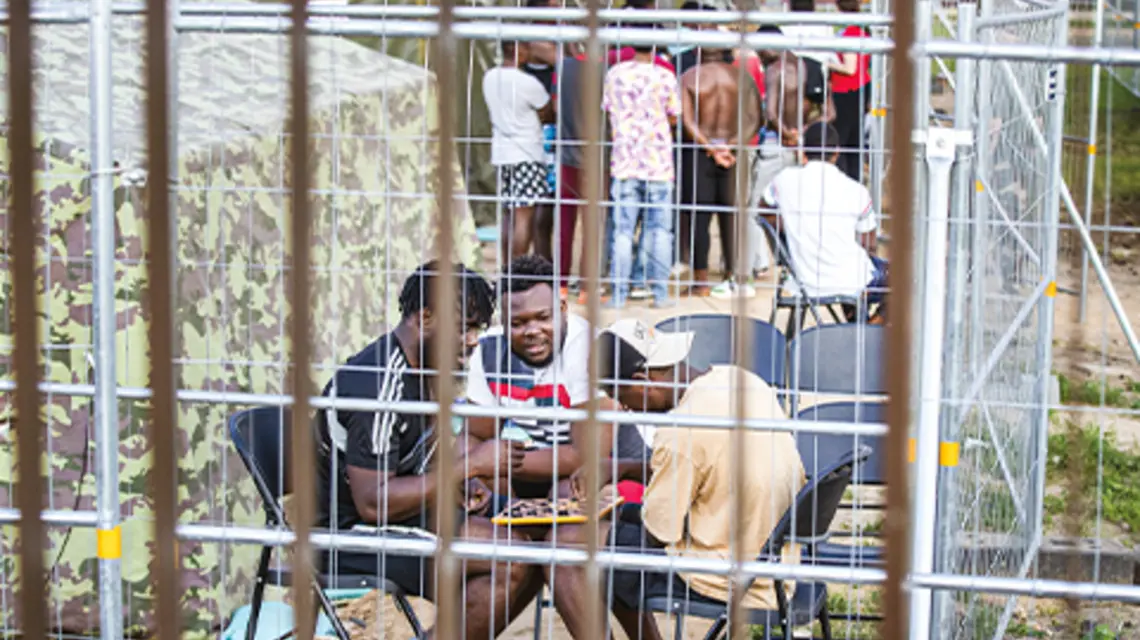 Migranci siedzą przed namiotem, grając w warcaby w nowo wybudowanym obozie dla uchodźców w Podbrodziu, około 40 km na północny wschód od Wilna, 8 lipca 2021 r. fot. Mindaugas Kulbis/AP Photo/East News