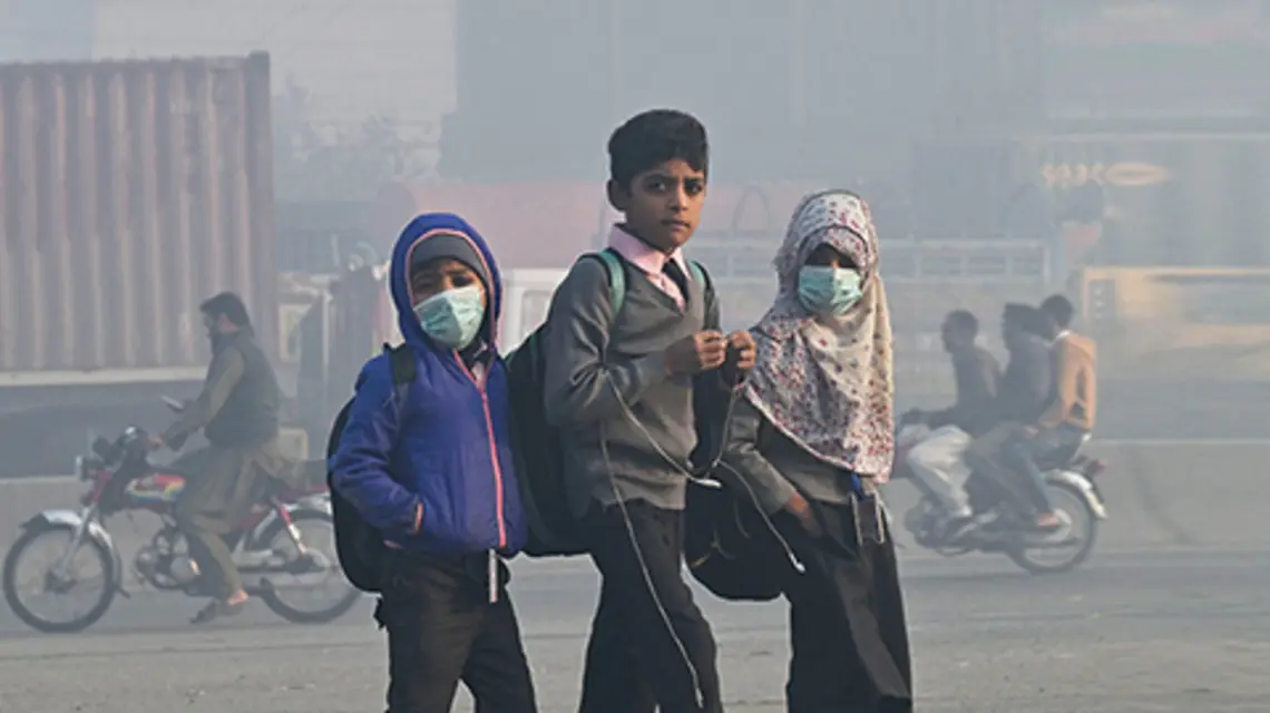 Dzieci w gęstym smogu idące do szkoły w Lahore (Pakistan), 1 grudnia 2022 r. fot. Arif ALI / AFP / East News