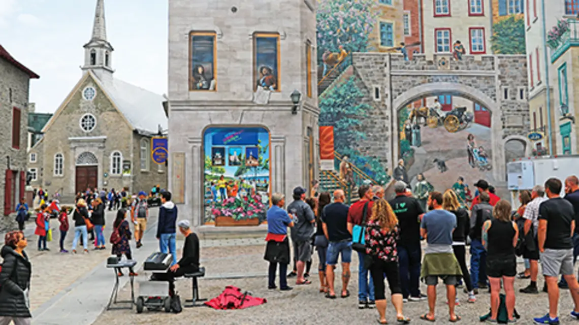 Miasto Quebec w Kanadzie, 14 czerwca 2023 r., mieszkańcy oglądają mural. Po lewej stronie kościół Matki Bożej Zwycięskiej to jedna z najstarszych świątyń w Ameryce Północnej. fot. Jakub Porzycki/Getty