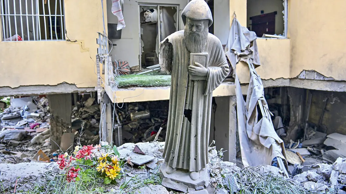 Figura św. Szarbela, maronickiego duchownego, mnicha i pustelnika, przed zniszczonym w izraelskim ataku budynkiem mieszkalnym w zamieszkanym głównie przez chrześcijan mieście Ain Saadeh nieopodal Bejrutu, 6 kwietnia 2026 r.