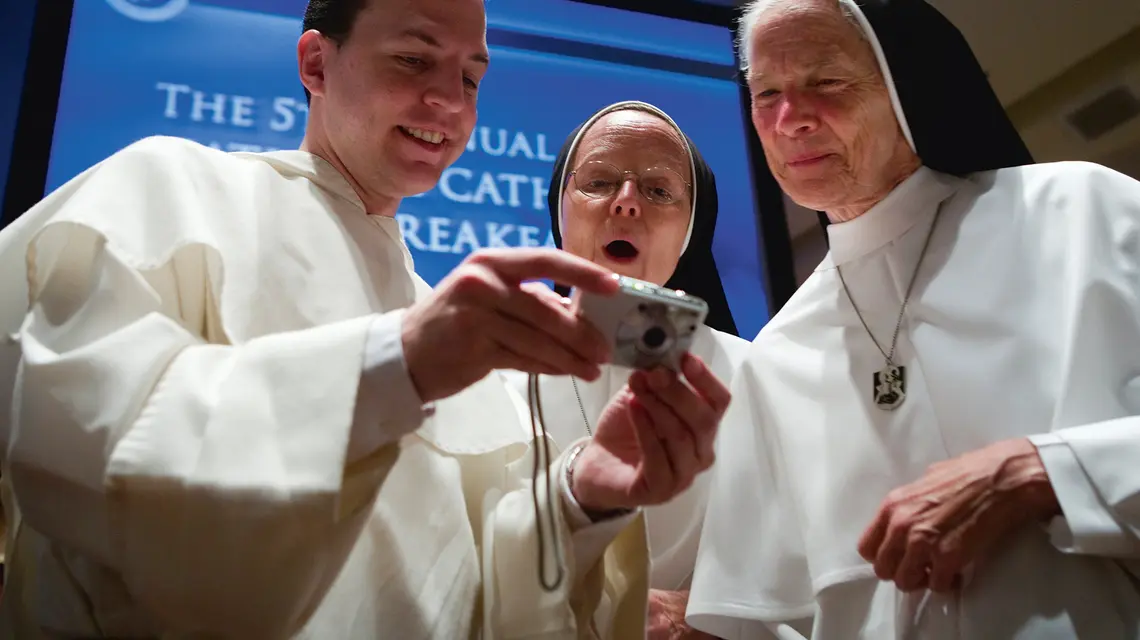 Brat Thomas Petri z Domu Studiów Dominikańskich w Waszyngtonie pokazuje zdjęcia Benedykta XVI siostrze Joseph Andrew OP i matce Assumpcie Long OP ze Zgromadzenia Sióstr Dominikańskich Maryi Matki Eucharystii z Ann Arbor, Waszyngton, 18 kwietnia 2008 r. | fot. Brendan Smialowski/Getty Images