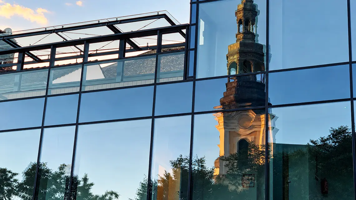 Lustrzane odbicie wieży Kościoła  Franciszkanów w przeszklonej fasadzie nowoczesnego budynku przy Placu Bernardyńskim w Poznaniu | Fot. ks. Wojciech Nowicki