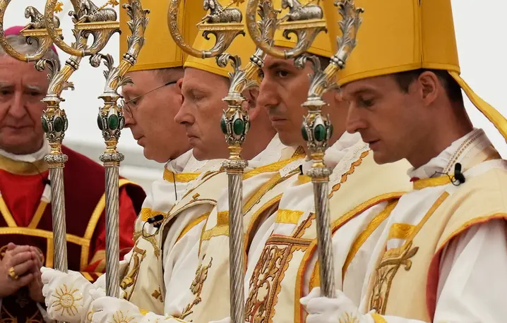 📸Nowo konsekrowani biskupi, od lewej: Pascal Schreiber, Michael Goldade, Michel Poinsinet de Sivry i Marc Hanappier, w mitrach i z pastorałami, modlą się na zakończenie ceremonii konsekracji w namiocie ustawionym przed seminarium Towarzystwa Świętego Piusa X w Écône w Szwajcarii, w środę 1 lipca 2026 roku. Fot. AP Photo/Baz Ratner / EastNews