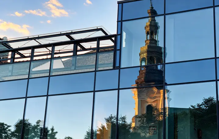 Lustrzane odbicie wieży Kościoła Franciszkanów w przeszklonej fasadzie nowoczesnego budynku przy Placu Bernardyńskim w Poznaniu | Fot. ks. Wojciech Nowicki