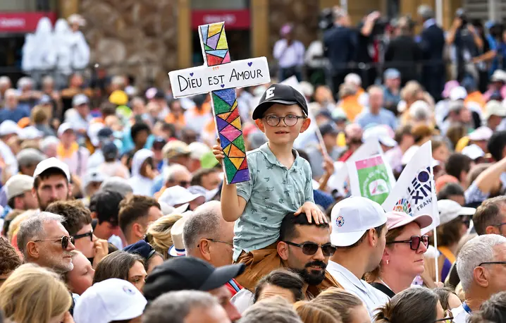 Chłopiec trzymający krzyż z napisem „Bóg jest miłością” przed mszą św. celebrowaną przez papieża Leona XIV w Katedrze św. Szczepana, Francja, Metz, 28 września 2026 r. | Fot. Emma Da Silva/AP/East News