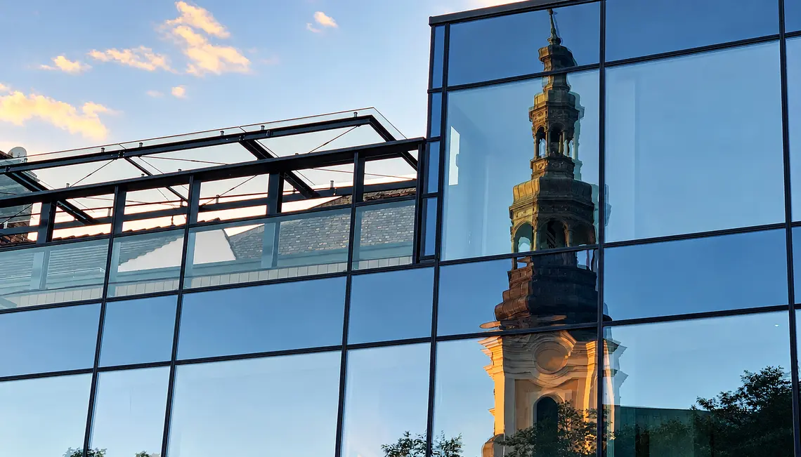 Lustrzane odbicie wieży Kościoła  Franciszkanów w przeszklonej fasadzie nowoczesnego budynku przy Placu Bernardyńskim w Poznaniu | Fot. ks. Wojciech Nowicki