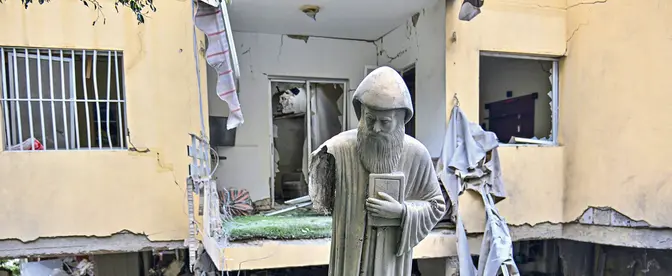Figura św. Szarbela, maronickiego duchownego, mnicha i pustelnika, przed zniszczonym w izraelskim ataku budynkiem mieszkalnym w zamieszkanym głównie przez chrześcijan mieście Ain Saadeh nieopodal Bejrutu, 6 kwietnia 2026 r.